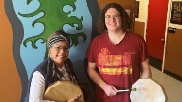 Female elder stands with male student