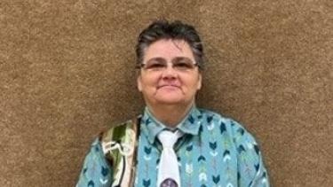 Métis Knowledge Keeper standing in front of brown wall