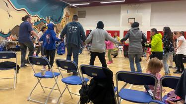 A group of people holding hands in a circle as part of the Pow Wow
