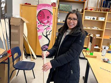 Female ISW at ASIA Sumas smiles while holding newly designed paddle