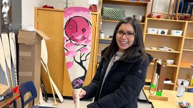 Female ISW at ASIA Sumas smiles while holding newly designed paddle