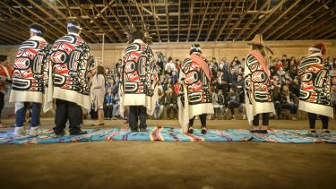 Six Aboriginal role models stand on blankets in the longhouse