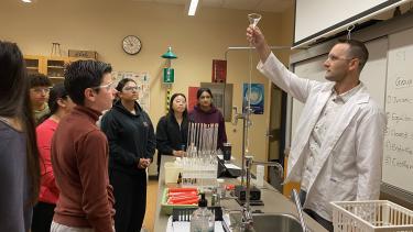Students watch as teacher demonstrates a chemistry lab