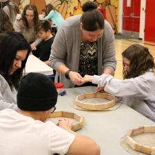 Two Indigenous Education staff members support 3 grade 5 students with their drums