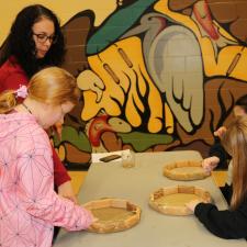 A female ISW helps three grade 5 students with their drums
