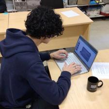 Male student sitting at a laptop completing school work
