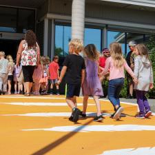 4 Kindergarten students walking across orange crosswalk holding hands