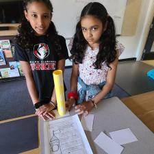 Two female students stand with completed project
