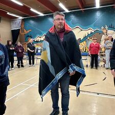 AbbyPD Constable standing in the gym, surrounded by students and staff after being blanketed